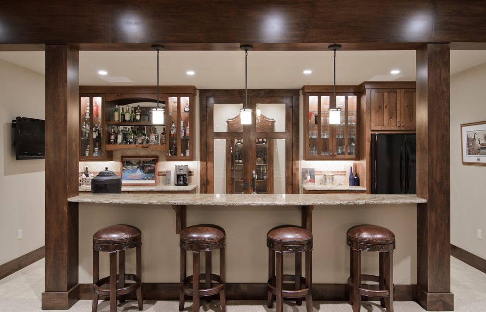 This is an example of a traditional galley seated home bar in Denver with glass-front cabinets, granite benchtops, dark wood cabinets and beige splashback.