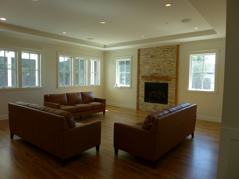 This is an example of an expansive country formal open concept living room in San Francisco with white walls, a wall-mounted tv, light hardwood floors, a standard fireplace, a tile fireplace surround, brown floor, recessed and panelled walls.