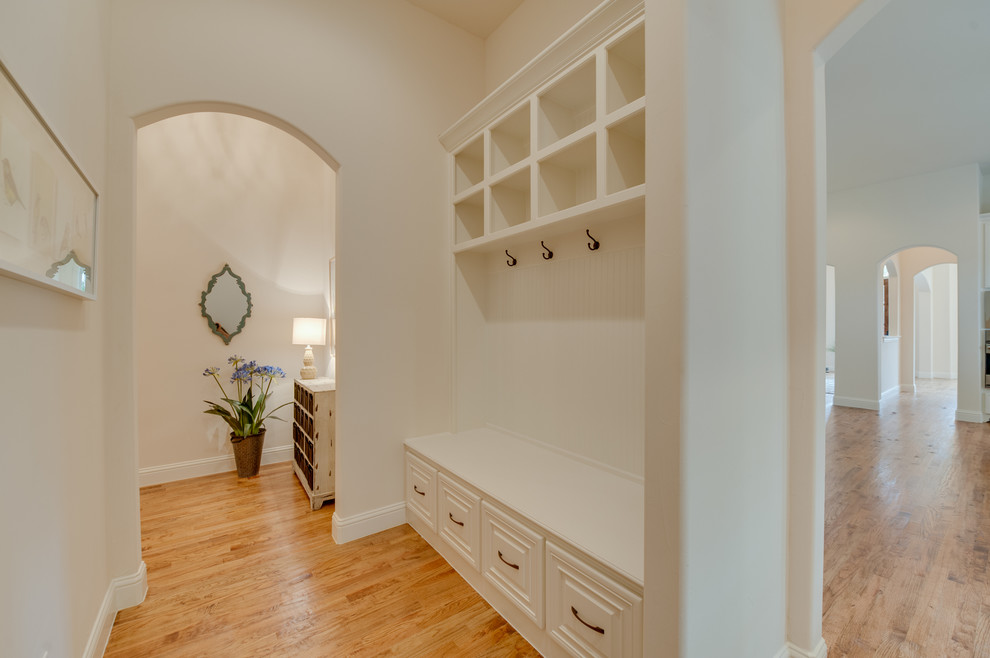 Design ideas for a mid-sized mediterranean hallway in Dallas with white walls and light hardwood floors.