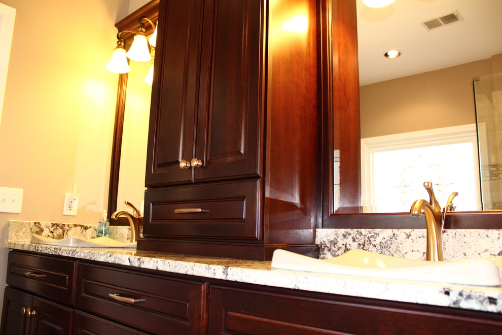 Photo of a large traditional master bathroom in Atlanta with a vessel sink, raised-panel cabinets, dark wood cabinets, granite benchtops, a drop-in tub, a corner shower, a two-piece toilet, brown tile, porcelain tile, brown walls and porcelain floors.