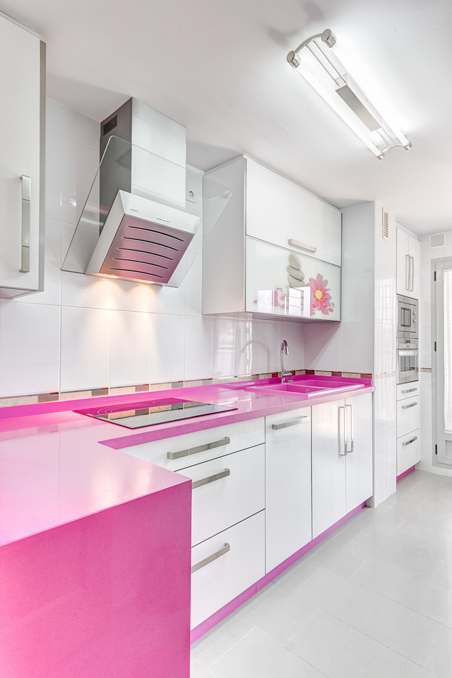 Photo of a mid-sized contemporary single-wall separate kitchen in Malaga with flat-panel cabinets, white cabinets, white splashback, a double-bowl sink, solid surface benchtops, ceramic splashback, stainless steel appliances, ceramic floors, no island and pink benchtop.