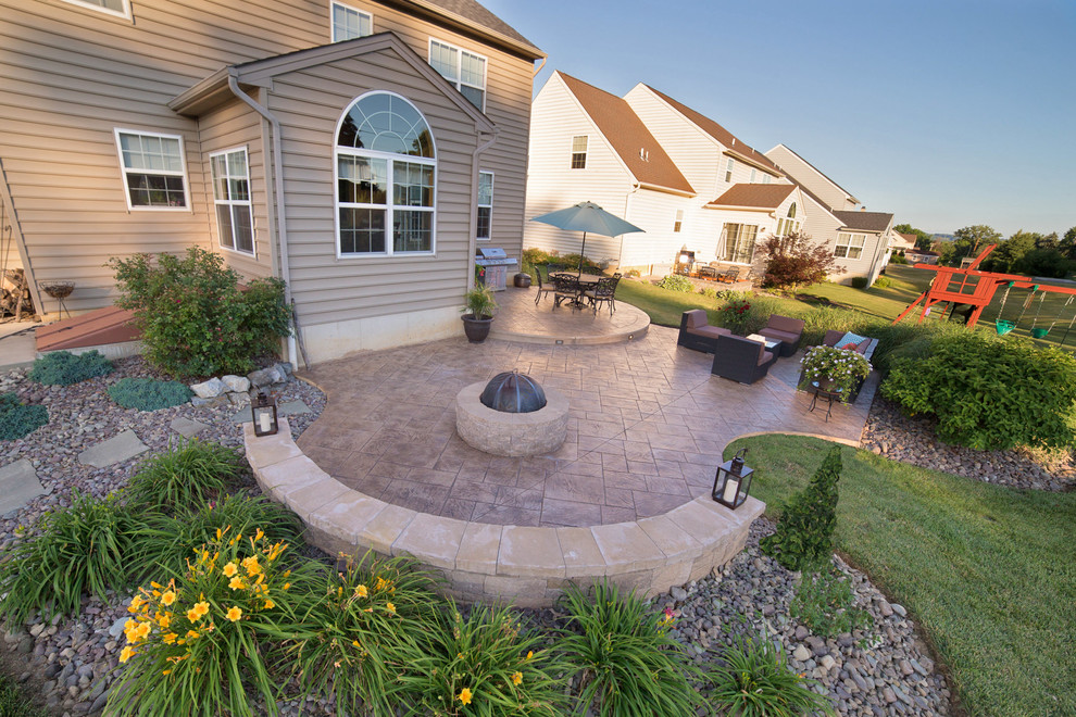 This is an example of a mid-sized traditional backyard patio in Philadelphia with a fire feature and stamped concrete.