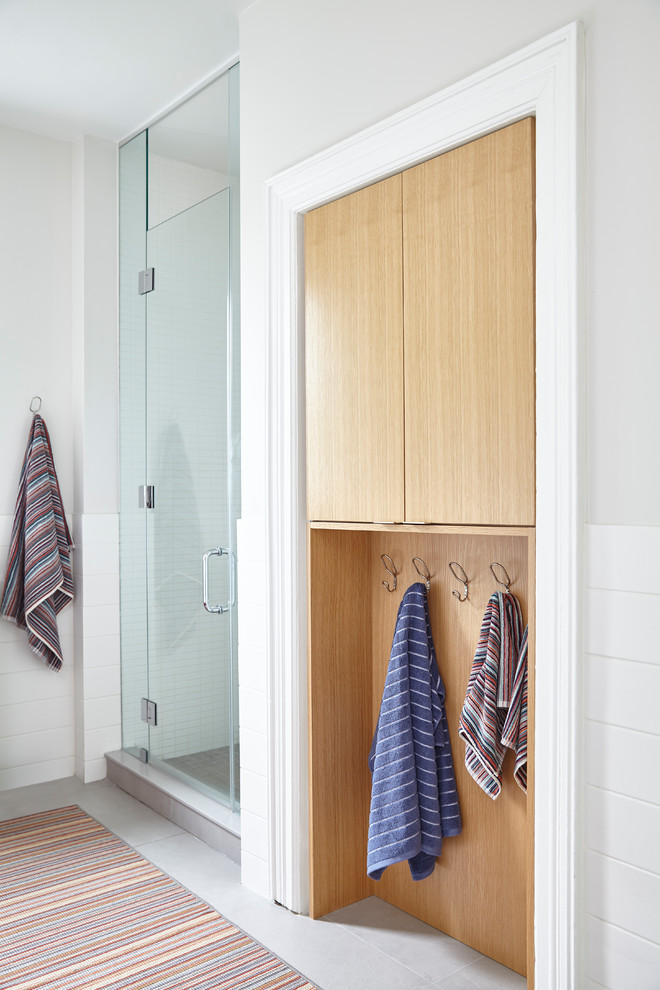 This is an example of a mid-sized scandinavian 3/4 bathroom in Toronto with flat-panel cabinets, light wood cabinets, an alcove shower, white tile, white walls, grey floor, a hinged shower door, a claw-foot tub, ceramic tile, ceramic floors and a wall-mount sink.