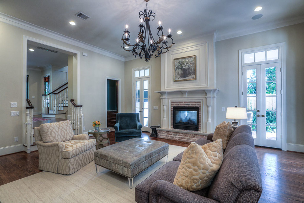 Design ideas for a large traditional enclosed family room in Houston with beige walls, dark hardwood floors, a standard fireplace, a brick fireplace surround and a wall-mounted tv.