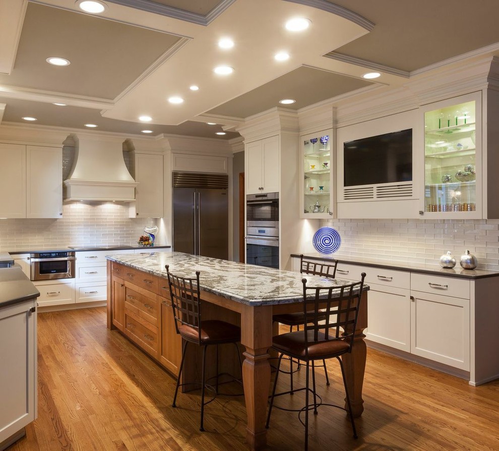 Example of a large transitional light wood floor kitchen pantry design in Cleveland with white backsplash, glass tile backsplash, stainless steel appliances and an island