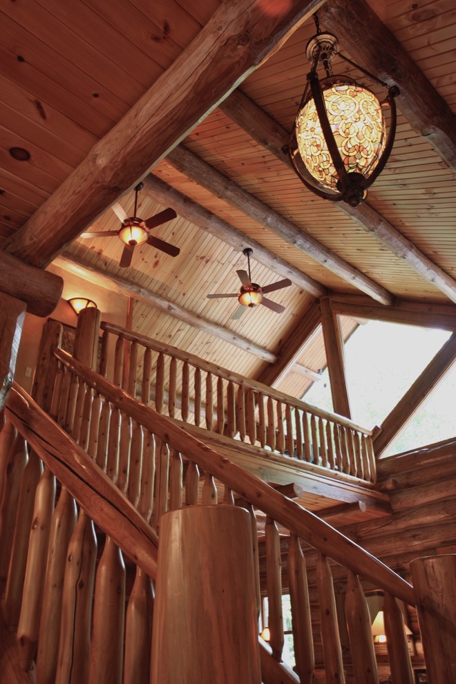 Example of a large mountain style wooden curved staircase design with wooden risers