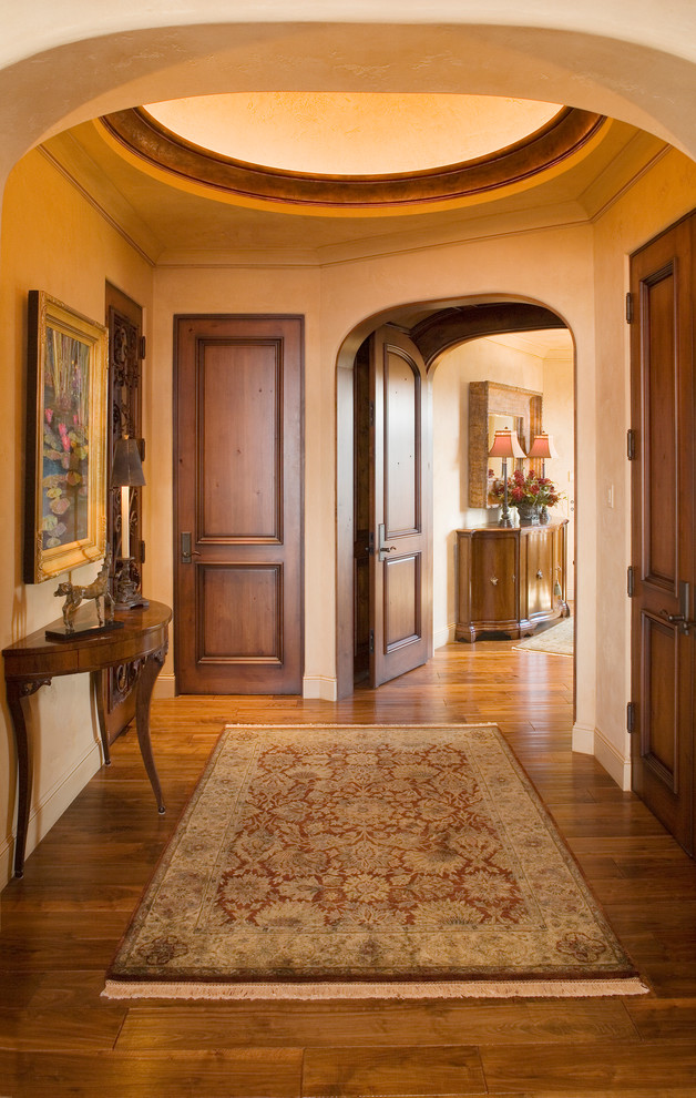 Inspiration for a mid-sized mediterranean foyer in Minneapolis with beige walls, medium hardwood floors, a single front door and a dark wood front door.