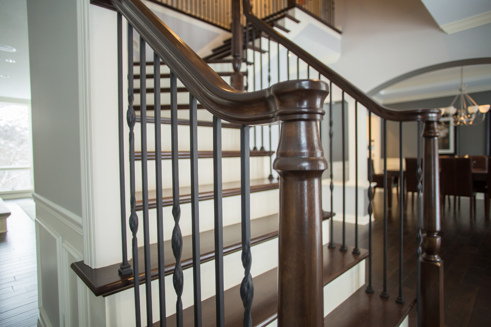 Large traditional wood l-shaped staircase in Minneapolis with painted wood risers and mixed railing.