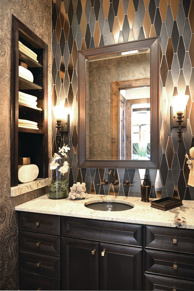 This is an example of a small contemporary powder room in Detroit with an undermount sink, recessed-panel cabinets, dark wood cabinets, gray tile, multi-coloured walls and white benchtops.