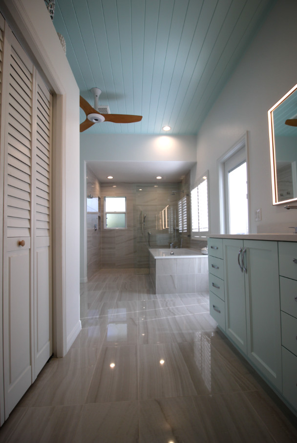 Inspiration for a mid-sized beach style master bathroom in Tampa with turquoise cabinets, a drop-in tub, an open shower, a one-piece toilet, white walls, a drop-in sink, brown floor, an open shower, white benchtops, an enclosed toilet, a double vanity and a built-in vanity.