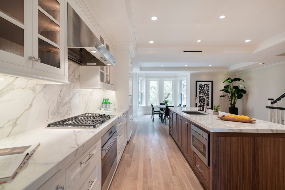 Design ideas for a transitional eat-in kitchen in Boston with white cabinets, grey splashback, stainless steel appliances, an undermount sink, recessed-panel cabinets, solid surface benchtops, light hardwood floors, with island, grey benchtop and recessed.