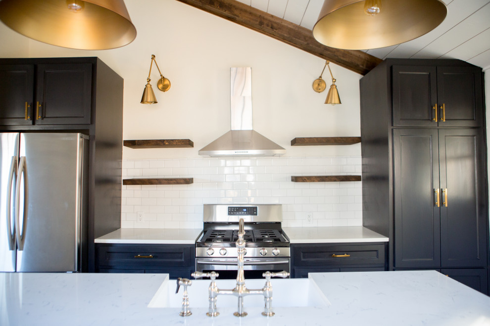 Inspiration for a large farmhouse single-wall brown floor and exposed beam kitchen remodel in Dallas with an undermount sink, black cabinets, ceramic backsplash, an island and white countertops