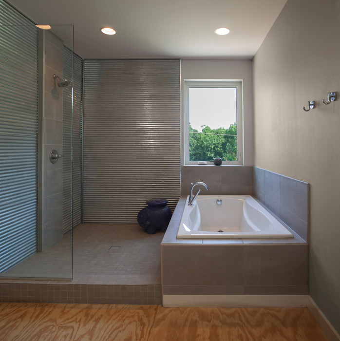 This is an example of a modern master bathroom in Other with a drop-in tub, an open shower, gray tile, ceramic tile, grey walls, plywood floors and tile benchtops.