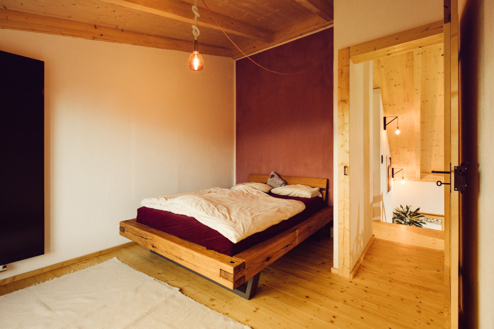 Rustic bedroom in Other with light hardwood flooring and a timber clad ceiling.