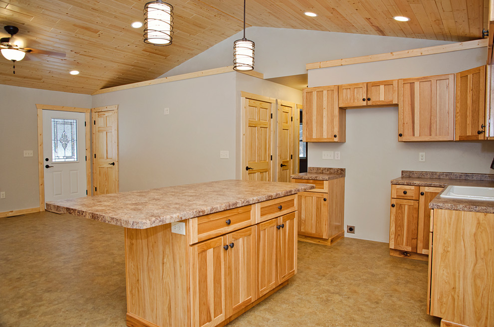 Example of a mid-sized mountain style l-shaped linoleum floor and brown floor open concept kitchen design with a drop-in sink, recessed-panel cabinets, light wood cabinets, laminate countertops and an island