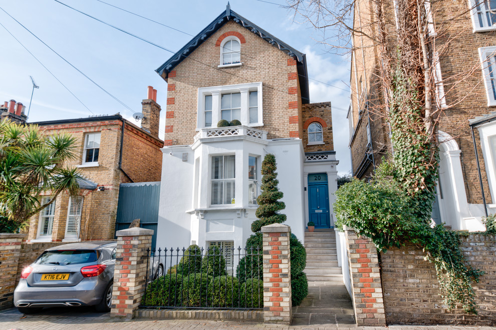 Photo of a large and multi-coloured brick detached house in London with three floors, a pitched roof and a mixed material roof.
