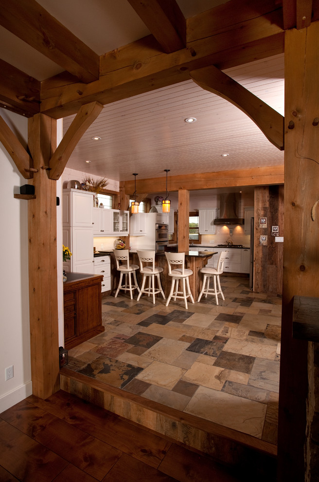 U-shaped slate floor eat-in kitchen photo in Toronto with white cabinets, stainless steel appliances and a peninsula