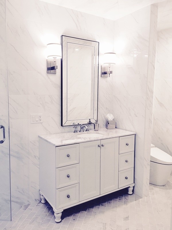 Large transitional white tile and porcelain tile marble floor claw-foot bathtub photo with white cabinets, a one-piece toilet, white walls, an undermount sink and marble countertops