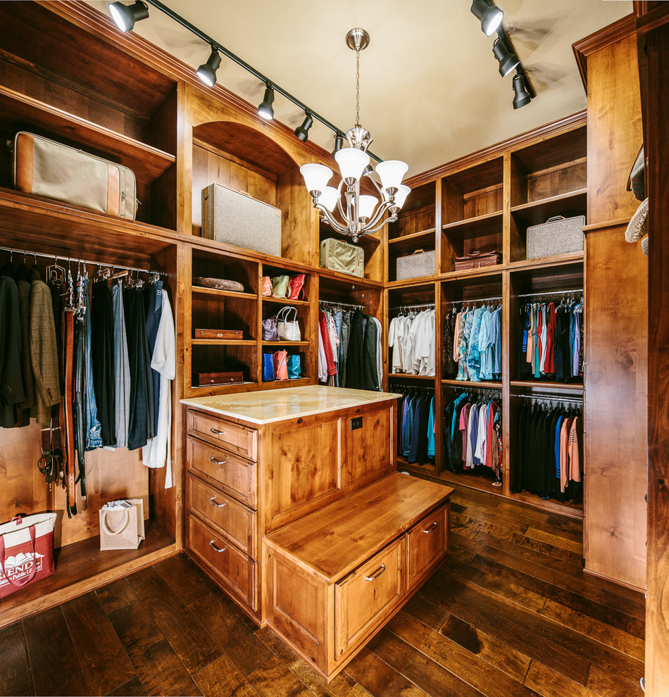 This is an example of a large traditional gender-neutral walk-in wardrobe in Austin with raised-panel cabinets, medium wood cabinets and dark hardwood floors.