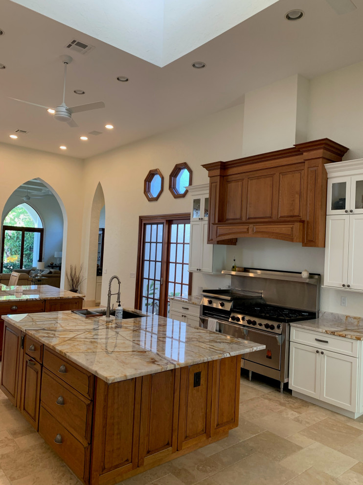 Example of a transitional beige floor eat-in kitchen design with a single-bowl sink, raised-panel cabinets, distressed cabinets, stainless steel appliances, two islands and multicolored countertops