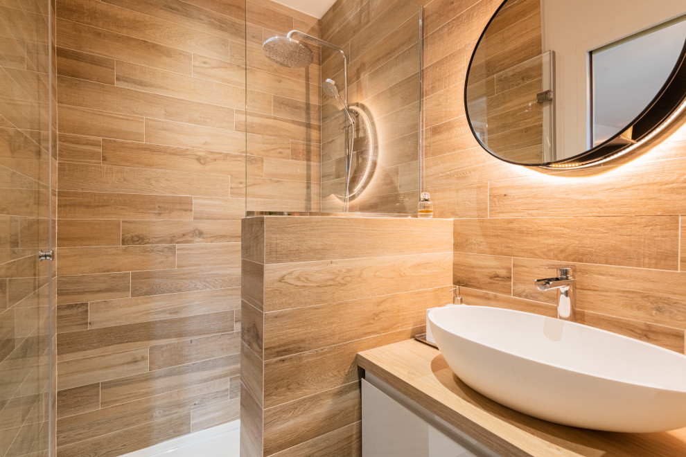 This is an example of a small rustic shower room bathroom in Paris with flat-panel cabinets, white cabinets, an alcove shower, a wall mounted toilet, brown tiles, wood-effect tiles, brown walls, slate flooring, a vessel sink, tiled worktops, grey floors, an open shower, beige worktops, a wall niche, a single sink and a floating vanity unit.