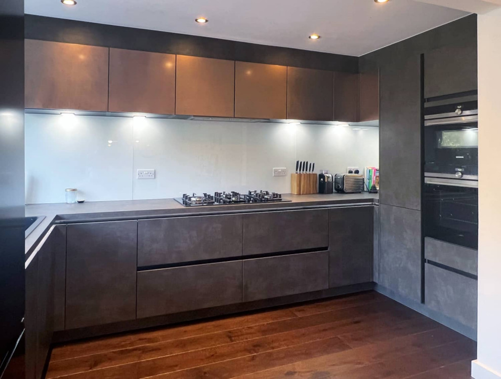 Photo of a small contemporary u-shaped enclosed kitchen in London with flat-panel cabinets and black appliances.