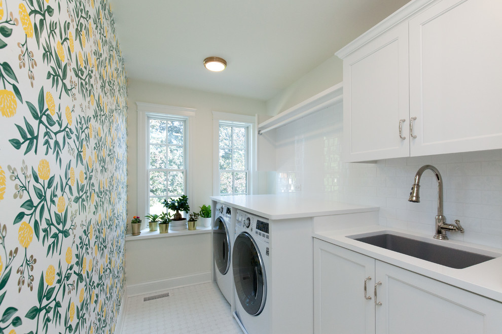 Mid-sized country single-wall dedicated laundry room in Chicago with an undermount sink, shaker cabinets, white cabinets, quartzite benchtops, yellow walls, ceramic floors, a side-by-side washer and dryer, white floor, white benchtop, white splashback, subway tile splashback and wallpaper.
