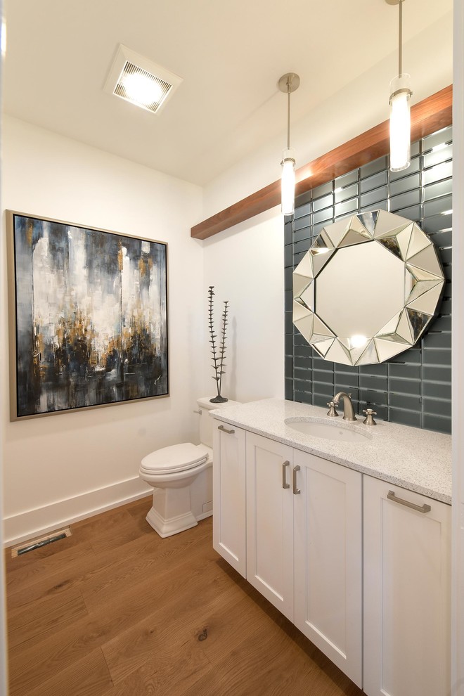 Inspiration for a traditional 3/4 bathroom with recessed-panel cabinets, white cabinets, a two-piece toilet, blue tile, white walls, medium hardwood floors, an undermount sink, a single vanity, a built-in vanity, glass tile and multi-coloured benchtops.