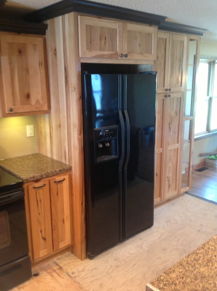 Open concept kitchen - mid-sized l-shaped open concept kitchen idea with raised-panel cabinets, light wood cabinets, laminate countertops, black appliances and a peninsula