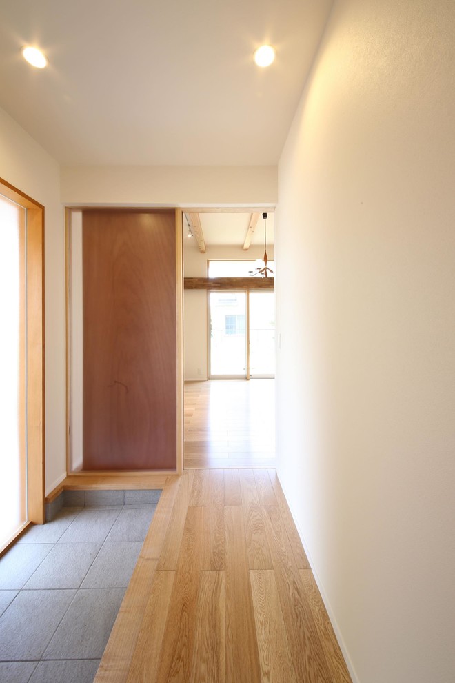 Idee per un corridoio etnico di medie dimensioni con pareti bianche, pavimento in compensato, una porta singola, una porta in legno bruno e pavimento marrone