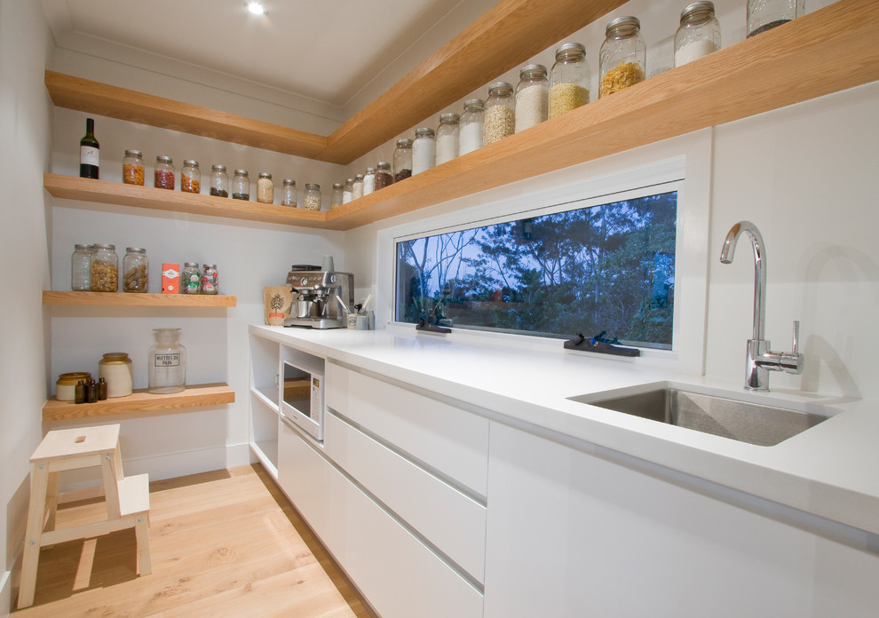 Contemporary kitchen pantry in Brisbane with an undermount sink, flat-panel cabinets, white cabinets, window splashback and light hardwood floors.