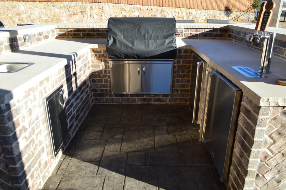 Photo of a large eclectic backyard patio in Dallas with an outdoor kitchen, stamped concrete and a roof extension.