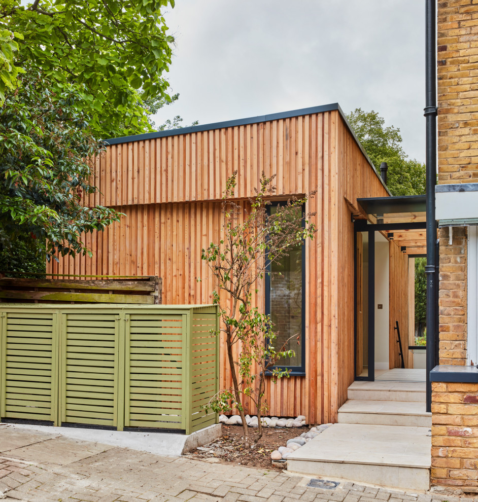 Diseño de fachada de casa bifamiliar contemporánea pequeña de dos plantas con revestimiento de madera, tejado plano, techo verde y panel y listón