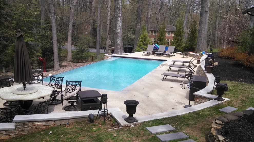 Photo of a mid-sized backyard custom-shaped pool in DC Metro with a water feature and concrete pavers.