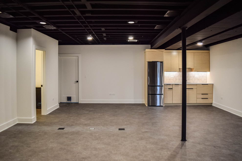 This is an example of a modern fully buried basement in Chicago with black walls, laminate floors and black floors.