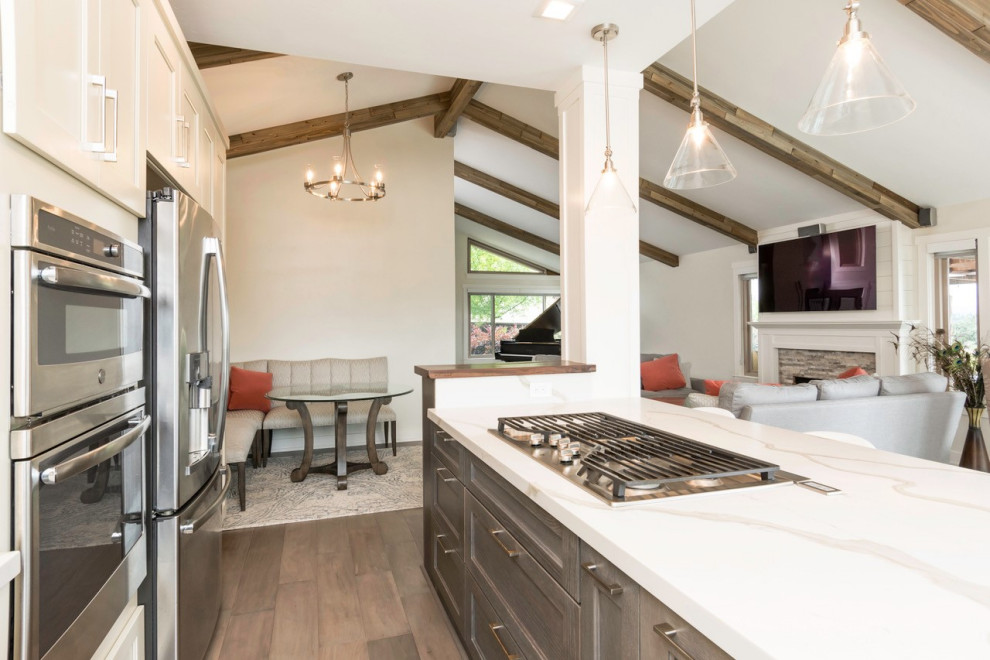 Example of a large transitional l-shaped dark wood floor eat-in kitchen design with an undermount sink, shaker cabinets, white cabinets, quartz countertops, blue backsplash, glass tile backsplash, stainless steel appliances, an island and white countertops