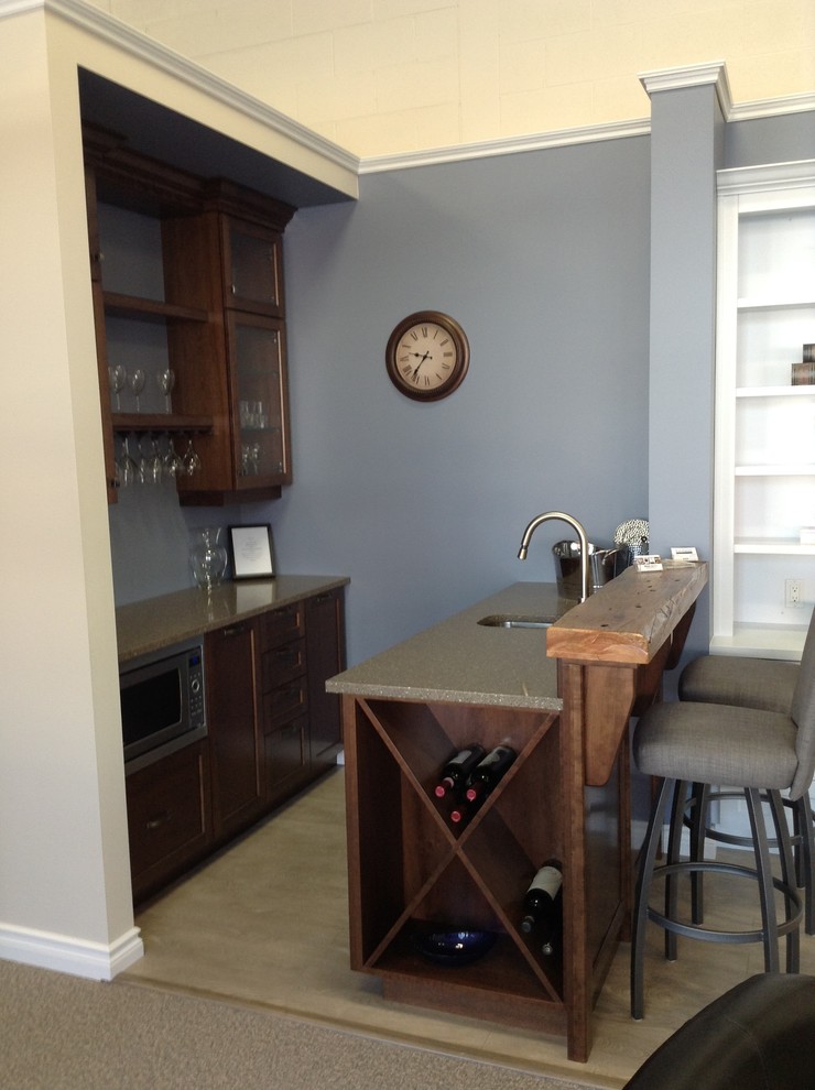 This is an example of a small transitional galley seated home bar in Toronto with an undermount sink, glass-front cabinets, dark wood cabinets, wood benchtops, light hardwood floors and beige floor.