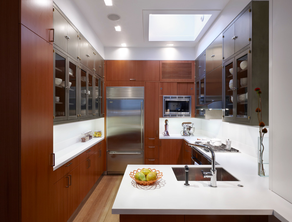Design ideas for a contemporary u-shaped kitchen in New York with an undermount sink, flat-panel cabinets, medium wood cabinets, white splashback, stainless steel appliances and medium hardwood floors.