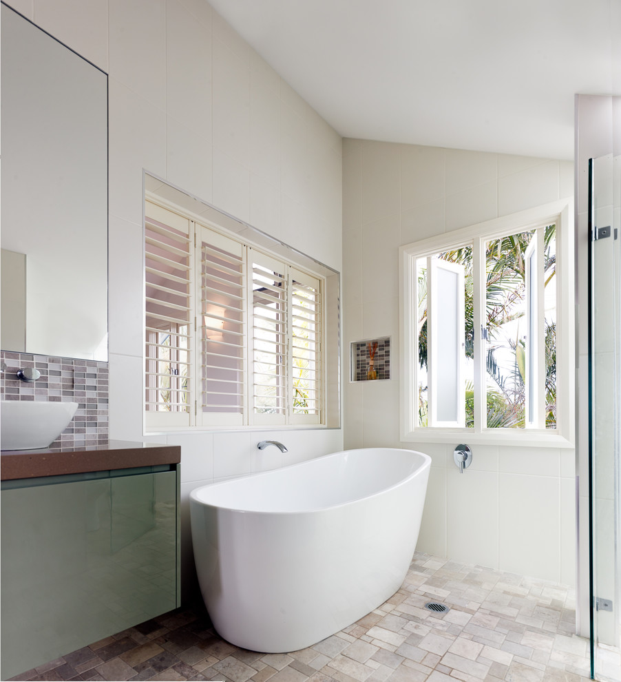 This is an example of a mid-sized contemporary bathroom in Sydney with a vessel sink, flat-panel cabinets, green cabinets, engineered quartz benchtops, a freestanding tub, a corner shower, a one-piece toilet, white tile, glass tile and white walls.