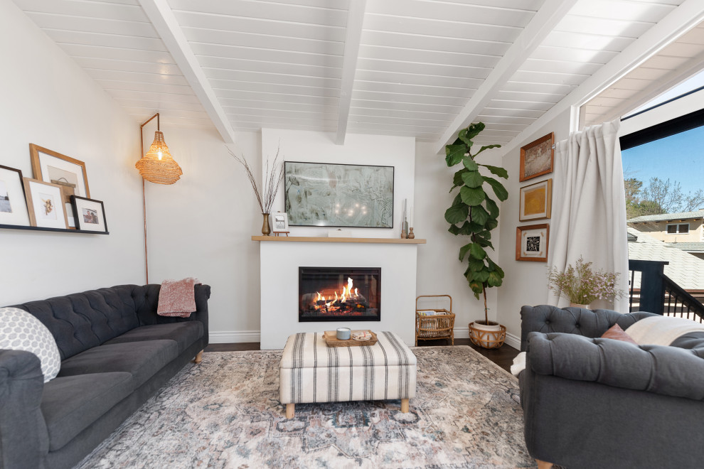 Idée de décoration pour une petite salle de séjour vintage ouverte avec un mur blanc, parquet clair, une cheminée standard, un manteau de cheminée en plâtre, un téléviseur indépendant, un sol beige et un plafond voûté.