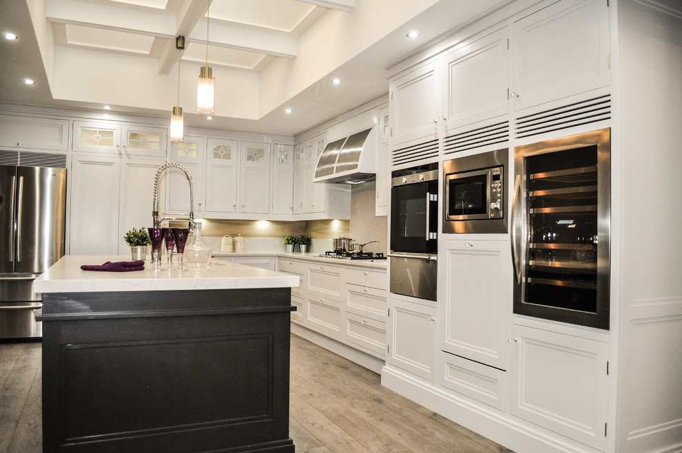 Design ideas for a large traditional u-shaped separate kitchen in Other with shaker cabinets, white cabinets, marble benchtops, white splashback, light hardwood floors, with island and beige floor.