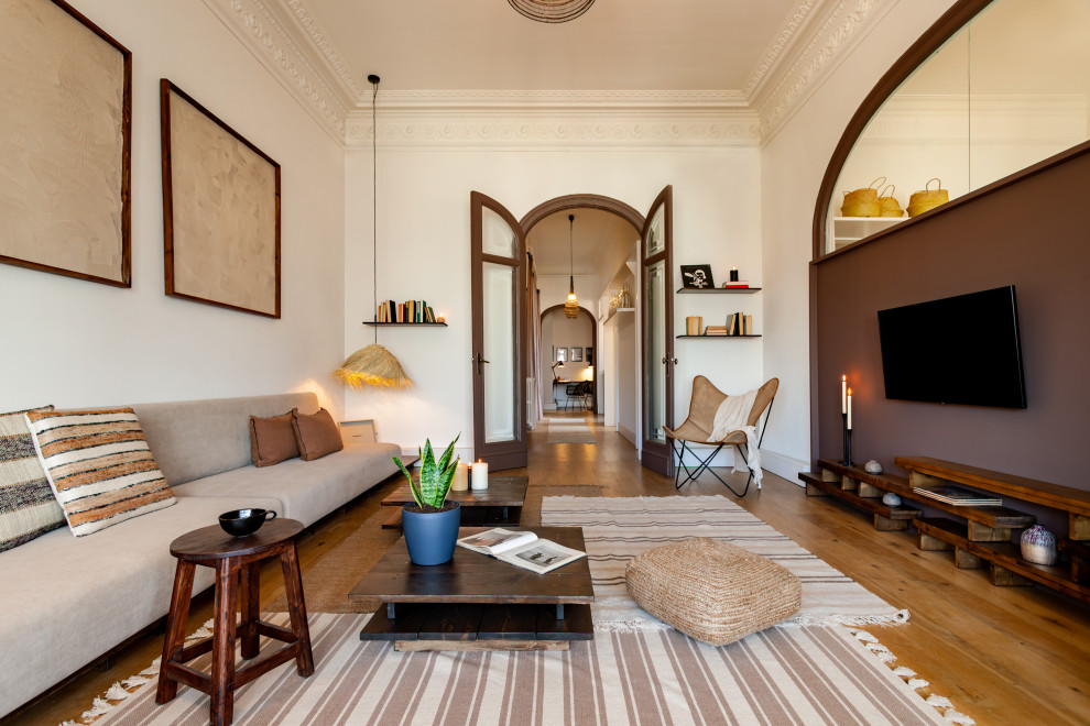 Modelo de sala de estar con rincón musical abierta tropical grande con paredes marrones, suelo de madera en tonos medios y televisor colgado en la pared