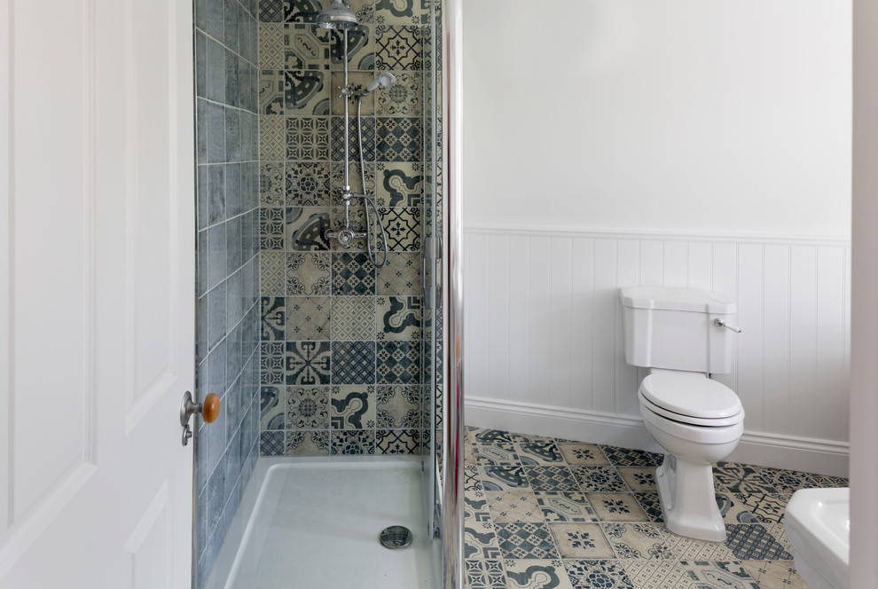 Photo of a small transitional 3/4 bathroom in Other with multi-coloured tile, ceramic tile, ceramic floors, a two-piece toilet, white walls, multi-coloured floor, a corner shower, a console sink and a sliding shower screen.