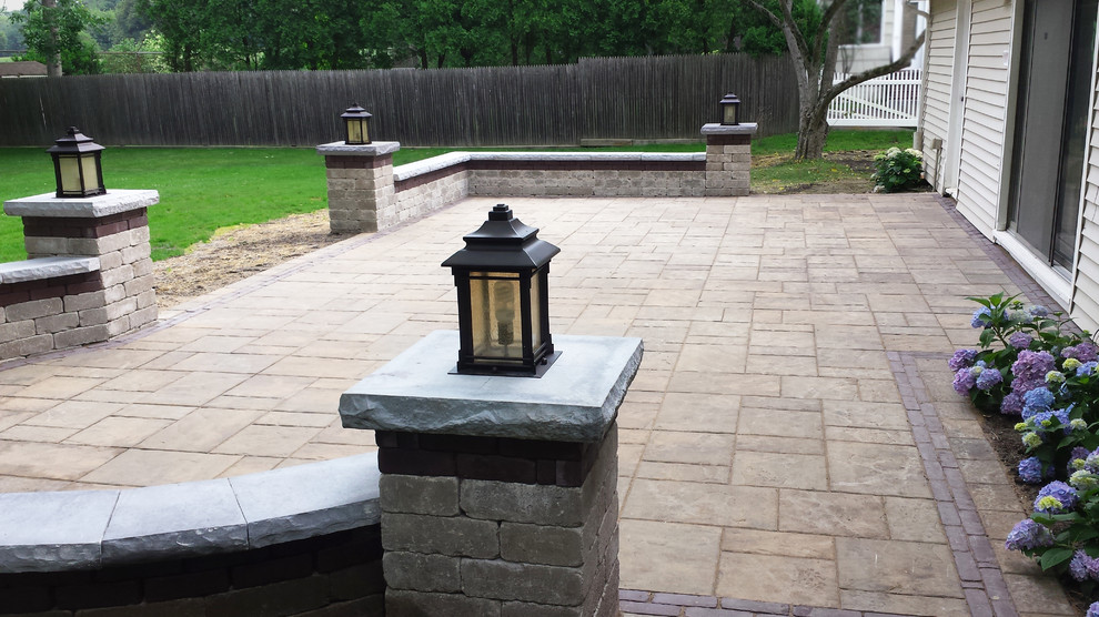 This is an example of a transitional backyard patio in New York with concrete pavers.