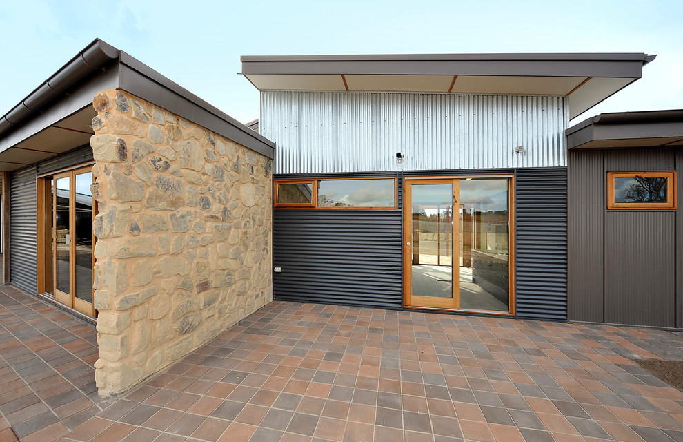 This is an example of a contemporary one-storey grey exterior in Adelaide with metal siding and a flat roof.