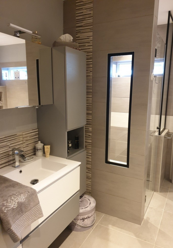 This is an example of a mid-sized contemporary master bathroom in Nice with flat-panel cabinets, grey cabinets, an undermount tub, a curbless shower, a wall-mount toilet, gray tile, ceramic tile, grey walls, ceramic floors, a trough sink, engineered quartz benchtops, beige floor, a hinged shower door and white benchtops.