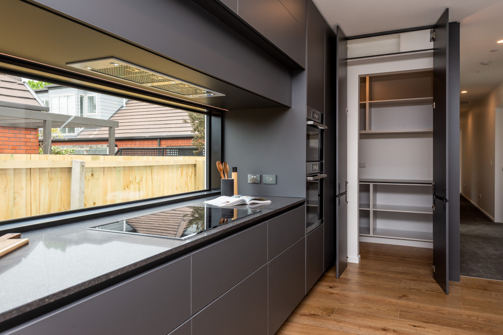 This is an example of a Mid-sized modern Galley eat-in kitchen in Christchurch With an Undermount Sink, Grey Cabinets, Quartz Benchtops, Light Hardwood Floors and with Island.