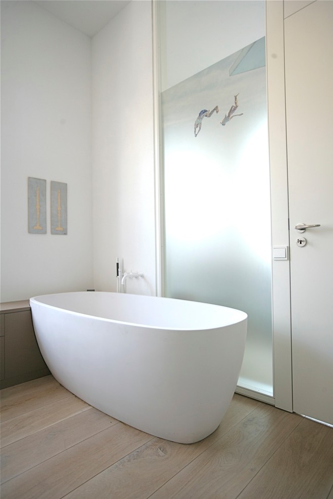 Design ideas for a large contemporary master bathroom in Other with a freestanding tub, a curbless shower, white tile, ceramic tile, light hardwood floors, a wall-mount sink, solid surface benchtops, beige floor, an open shower, white benchtops, a shower seat, a double vanity and a floating vanity.