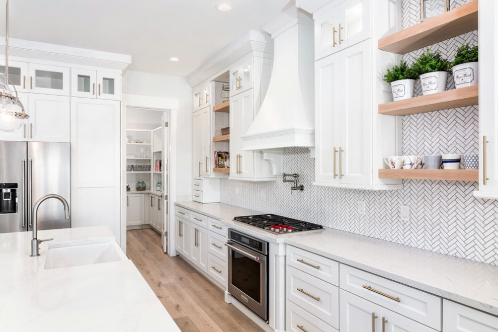 Inspiration for an expansive country l-shaped eat-in kitchen in Salt Lake City with a farmhouse sink, shaker cabinets, white cabinets, quartz benchtops, white splashback, marble splashback, stainless steel appliances, light hardwood floors, with island, brown floor and white benchtop.