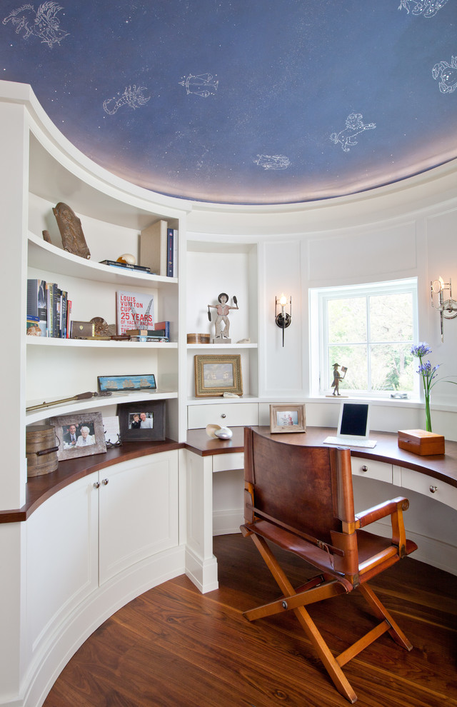 Beach style built-in desk medium tone wood floor study room photo in Boston with white walls